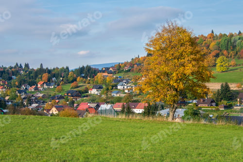 Preview: Rural autumn landscape with a green meadow against the background of a village. Krahule, Slovakia.