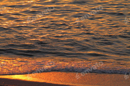Preview: Golden sea waves and sand at sunset, closeup