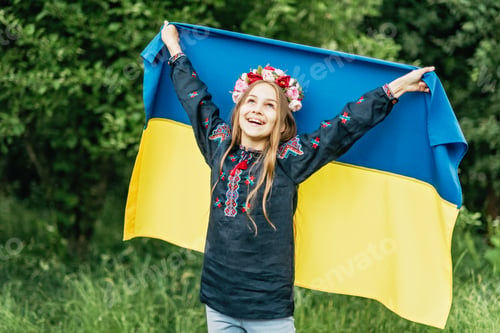 Preview: Ukrainian child girl in embroidered shirt vyshyvanka with yellow and blue flag of Ukraine in field.