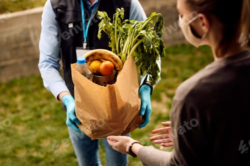 Preview: Unrecognizable courier delivering fresh groceries to customer's home during coronavirus pandemic.