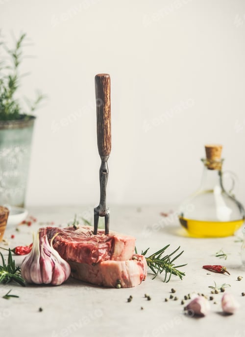 Preview: Raw meat steak with ingredients and meat fork on kitchen table
