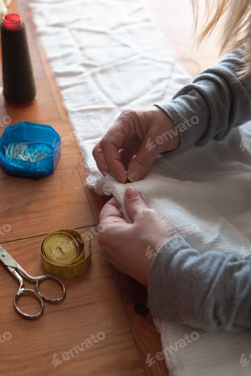 Preview: Female carefully sewing white cloth