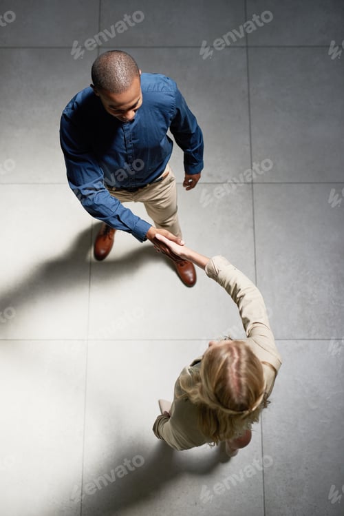 Preview: High angle shot of two businesspeople shaking hands in an office