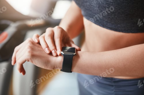 Preview: Checking results. CLose up of sporty woman looking at her sport bracelet on hand after workout at