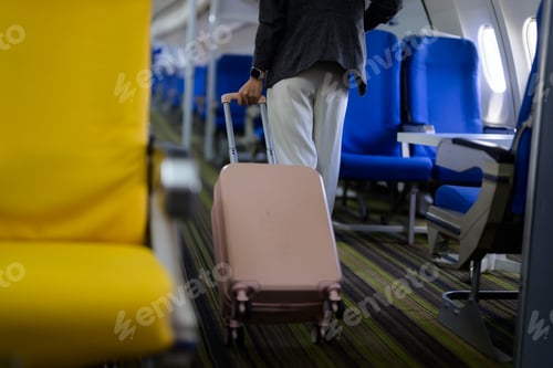 Preview: Passenger pulling suitcase walking in airplane aisle