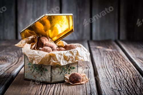 Preview: Chocolate balls in golden box on old wooden table
