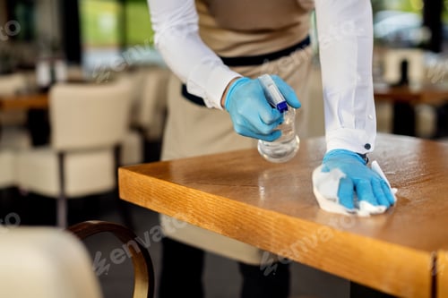 Preview: Close-up of waiter disinfecting cafe tables after work.