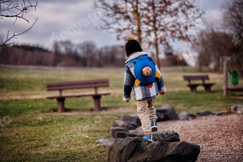 Preview: Child Balancing on Rocks with Rocket Backpack in Park