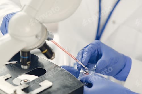 Preview: Unrecognizable lab worker inspecting blood sample under microscope