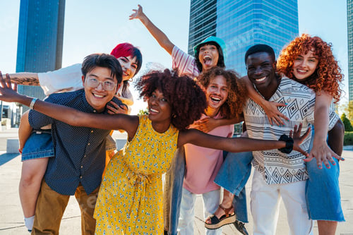 Preview: Multiethnic group of young friends meeting and having fun outdoors
