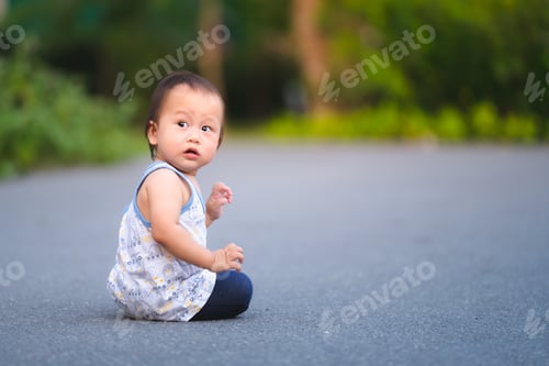 Preview: Little baby boy 1 year old sits on road. Child was looking back with questioning look on his face.