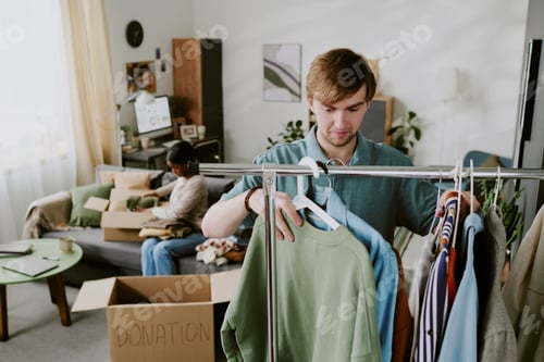Preview: Adult Man Sorting Donated Clothes for Home Charity Campaign