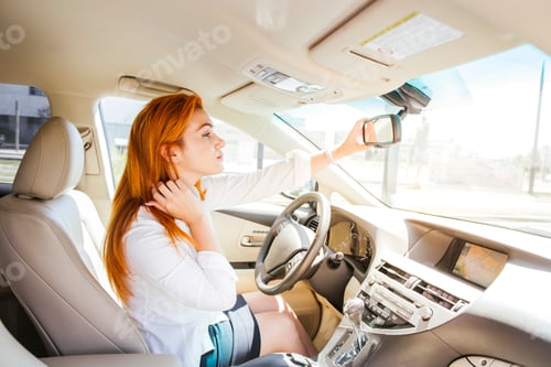 Preview: Business woman in a car checking her look in the rear-view mirror
