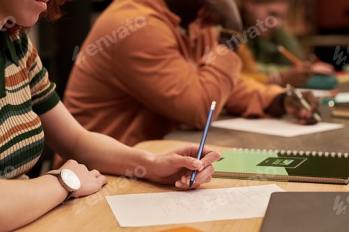Preview: Young Woman Writing Notes during Group Study Session Indoors