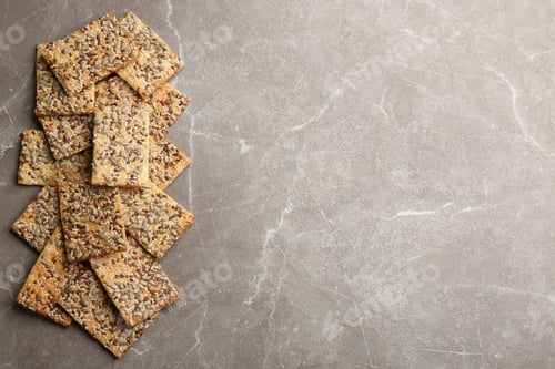 Preview: Many delicious crackers on grey table, flat lay. Space for text