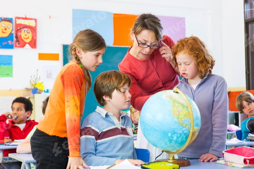 Preview: Primary schoolboys and girls looking at globe in classroom