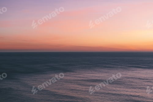 Preview: View out to sea over the ocean at dusk, the sunset light on the horizon and calm undulating sea