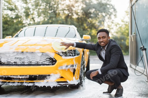 Preview: Handsome African American man in business suit washing car hood