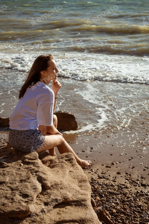 Preview: Young woman sitting by the sea in summer