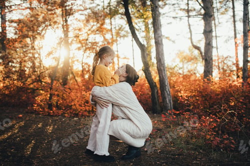 Preview: Young mother and her daughter walking together in a beautiful autumn forest.