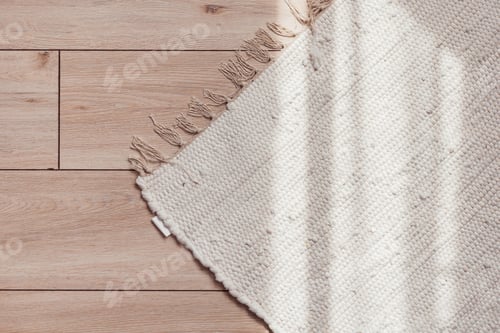 Preview: Wicker beige rug on wooden parquet floor with sunlit, top view.