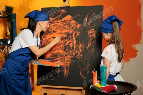 Preview: Woman teaching kid to paint canvas artwork