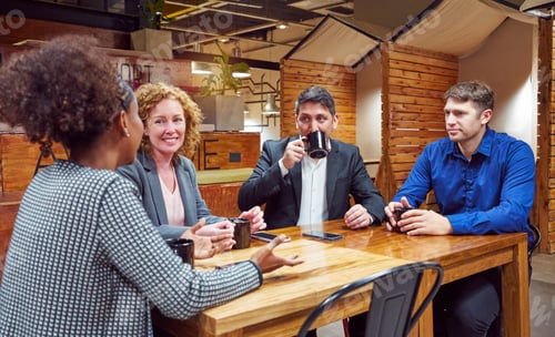 Preview: four businesspeople sitting indoors drinking coffee talking