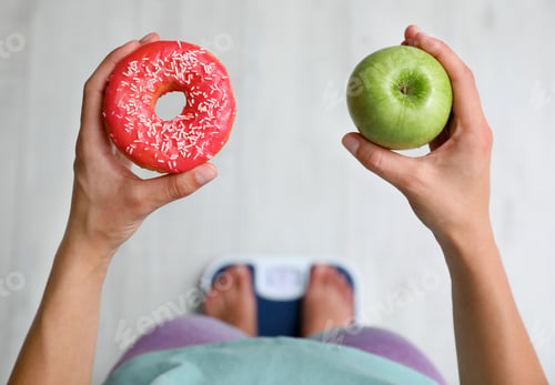 Preview: Choice concept. Top view of woman with apple and doughnut standing on scales, closeup