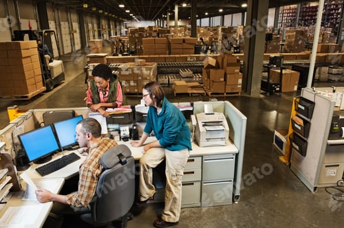 Preview: Workers studing a document on a computer at the front desk of a distribution warehouse.