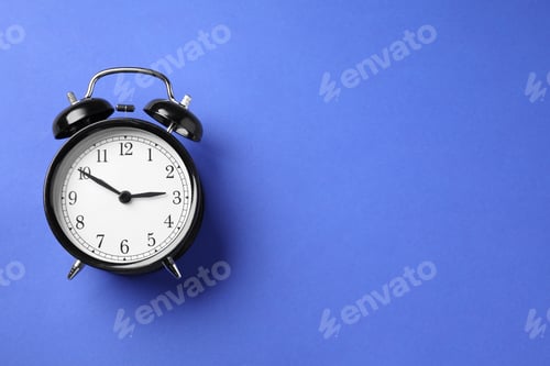Preview: One black alarm clock on blue background, top view. Space for text