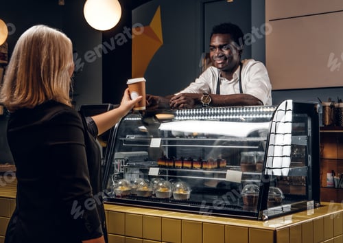 Preview: African barista gives the ordered coffee customer of modern coffee shop