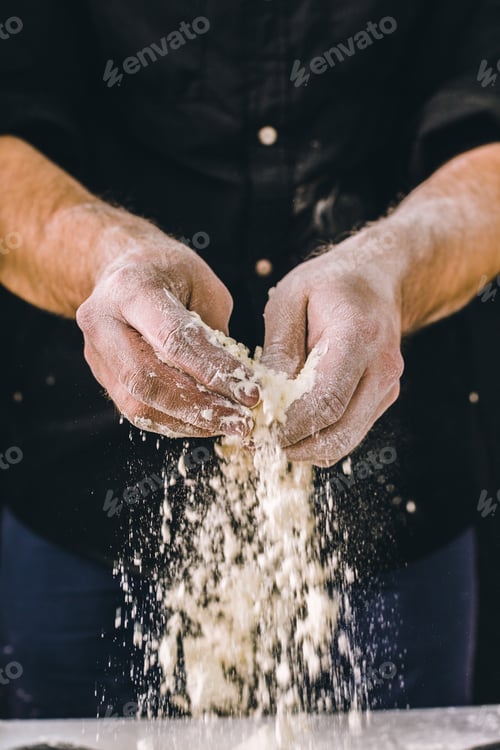 Preview: Hands sprinkle flour while preparing dough in a kitchen during daytime