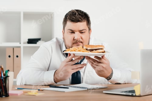 Preview: overweight businessman with hamburger and french fries in office