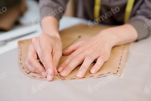 Preview: Young female tailor pinning paper workpiece to piece of fabric