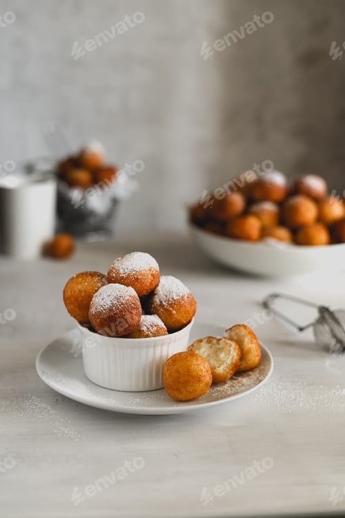 Preview: Delicious doughnuts in powdered sugar in a white ceramic bowl on the table.