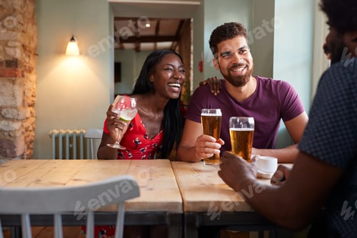 Vista previa: Young couple and an older man drinking at a table in a pub