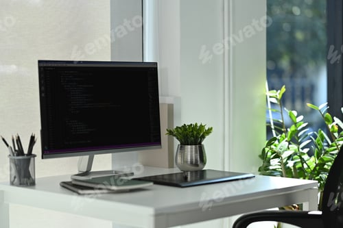 Preview: Computer monitors with coded data, supplies on wooden table in software development office.