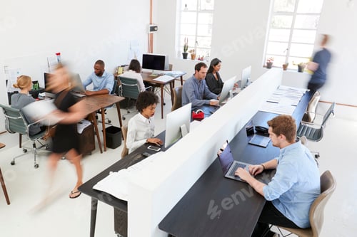 Preview: Young colleagues at computers in a busy open plan office