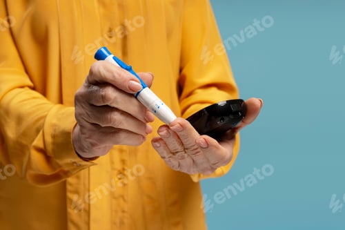 Preview: Senior woman checking blood sugar level using lancet pen and glucometer