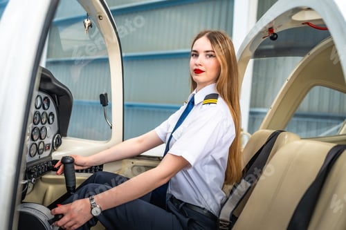 Preview: Female pilot sitting in cockpit holding control stick of small airplane