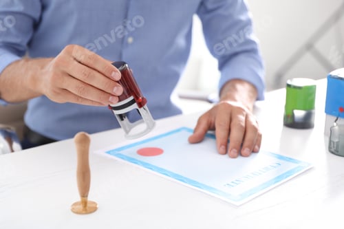 Preview: Male notary stamping document at table in office, closeup