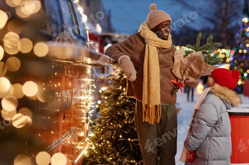 Preview: Happy African American family shopping at Christmas market in winter