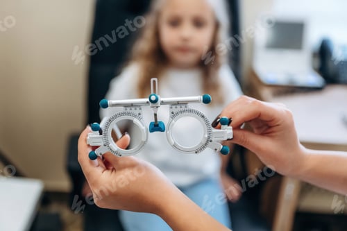 Preview: holding device for measuring sight sharpness. Little girl at the ophthalmologist clinic with doctor