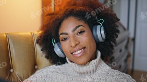 Preview: Cheerful model listening headphones portrait. Happy curly woman smiling camera