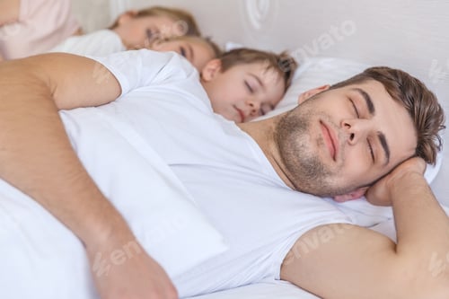 Preview: young family sleeping together in bed