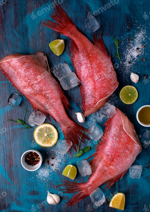 Preview: Redfish or perch with other ingredients and ice around on the blue table. Top view.