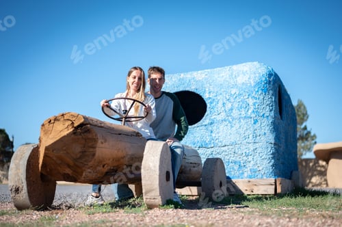 Preview: Smiling couple riding a automobile made out of wood