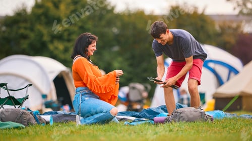 Preview: Young Couple Setting Up Tent At Summer Music Festival Unpacking Camping Equipment
