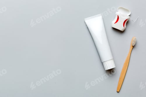 Preview: toothpaste and toothbrush top view with copy space on colored background. Flat lay