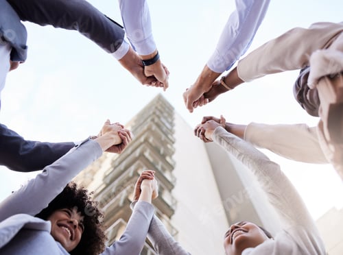 Preview: Low angle show of a diverse group of businesspeople huddled outside together and holding hands